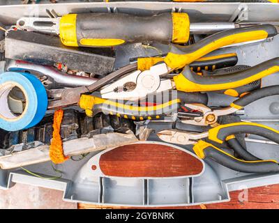 Kunststoffgehäuse mit einem funktionierenden Schlosserwerkzeug. Zangen und Schraubendreher. Schraubenschlüssel. Elektroband und Messer. Schlosserzubehör. Mitarbeiter-Tool. Zurück Stockfoto