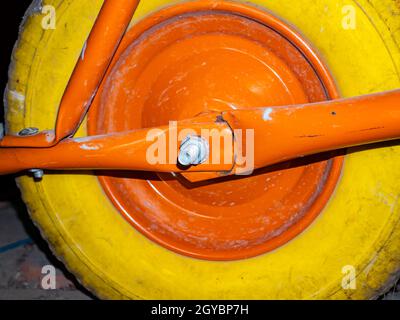 Ein gelbes Rad mit einer orangefarbenen Scheibe einer Gartenrampe. Gelber Gummireifen. Fahrzeug. Reifenservice. Hintergrundbild. Ort für Ihren Text. Po Stockfoto