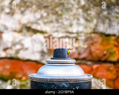 Schwarzer Knopf der Sprühfarbe auf einem Ziegelsteinwand Hintergrund. Sprühfarbe. Graffiti an den Wänden. Gebäudesektor. Lackierung des Autos. Drucktastenmechani Stockfoto