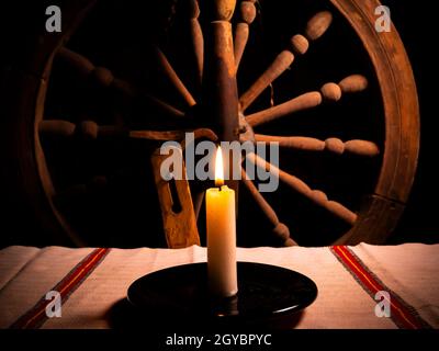 Brennende Wachskerze auf einem Tisch im Dunkeln. Flamme der Wachskerze Feuer. Feuer der Erinnerung. Flamme im Dunkeln. Ukrainische Kultur. Retro-Style. Handtuch mit Ukr Stockfoto