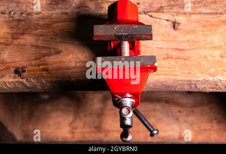 Schlosser Werkzeug Metall-Schraubstock auf einem Holztisch befestigt. Mechaniker für Schraubstock aus Eisen. Arbeitswerkzeug des Masters. Kundendienst. Hintergrundbild. Plac Stockfoto