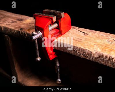 Schlosser Werkzeug Metall-Schraubstock auf einem Holztisch befestigt. Mechaniker für Schraubstock aus Eisen. Arbeitswerkzeug des Masters. Kundendienst. Hintergrundbild. Plac Stockfoto