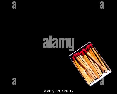 Karton mit Holzpappen auf schwarzem Hintergrund. Zündhölzer Streichholzschachtel. Roter Schwefel. Schwarzer Hintergrund. Holzwerkstoff. Hintergrundbild. Stockfoto