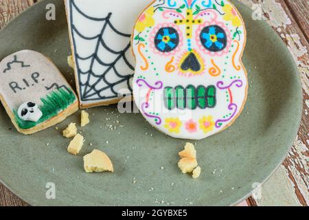 Nahaufnahme von butterbutterigen Keksen mit Halloween-Motiv auf einem grünen Teller. Stockfoto