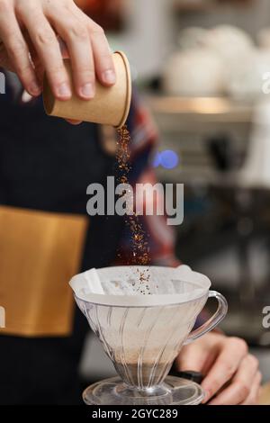 Männliche Hände gießen im Café gemahlenen Kaffee in den Filter. Stockfoto