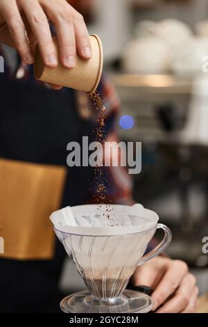 Männliche Hände gießen gemahlenen Kaffee in den Filter, um frisch gebrühten Kaffee zuzubereiten. Stockfoto