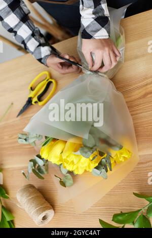 Floristin Frau macht ein Bouquet von frischen gelben Tulpen. Studio mit Blumenmuster Stockfoto