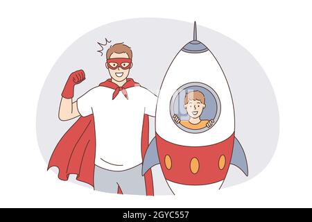 Glückliche Vaterschaft und Kindheitskonzept. Glücklich lächelnder Vater Mann in Superhelden-Kostüm und sein Sohn in Spielzeug Rakete spielen Blick auf Kamera Gefühl exci Stockfoto