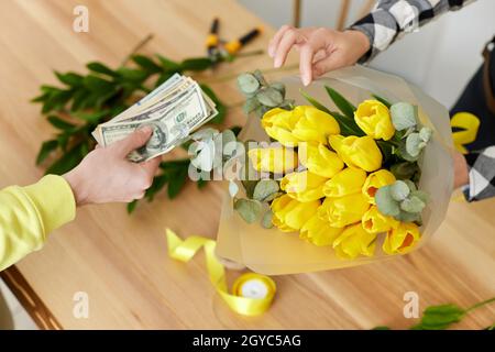 Geschäftsmann zahlen für Blumen im Blumenladen, Nahaufnahme. Barzahlung für Blume Stockfoto