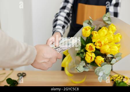 Mann, der Geld für die Zahlung Blumen an Floristin Frau. Stockfoto
