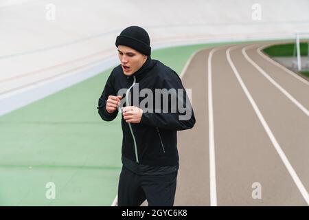 Selbstbewusster junger Mann, der sich vor dem Rennen im Stadion aufwärmen muss Stockfoto