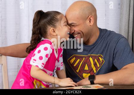 5-jähriges Mädchen zu Hause mit ihrem Vater, lacht zusammen, liebevoller Moment Stockfoto