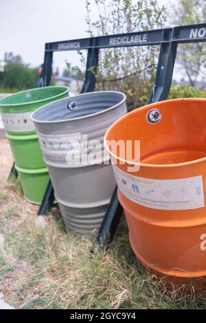 Spanische Schilder über bunten Mülltonnen im Park Stockfoto