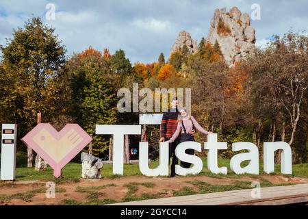 Ein paar Touristen posieren für Foto von Ich liebe Tustan Zeichen im Naturpark im Herbst. Reisen in der Ukraine in den Karpaten Stockfoto
