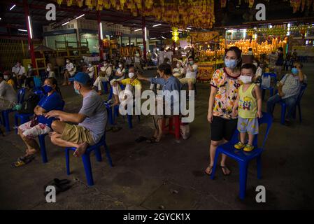 Bangkok, Thailand. Oktober 2021. Menschen, die Gesichtsmasken tragen, um die Ausbreitung des Coronavirus zu verhüten, sehen sich die Aufführung der chinesischen Operntruppe im Chow Sue Kong-Schrein während des jährlichen vegetarischen Festivals in Bangkok an. Das Vegetarische Festival, das von chinesischen Einwanderern ins Leben gerufen wurde, findet im neunten Mondmonat statt und dauert neun Tage. Während der neuntägigen Periode werden sich eifrige Anhänger vom Verzehr von Fleisch enthalten, nur vegetarisches Essen konsumieren und Verdienste leisten, alles in der Hoffnung, ihren Körper und Geist zu reinigen. Kredit: SOPA Images Limited/Alamy Live Nachrichten Stockfoto