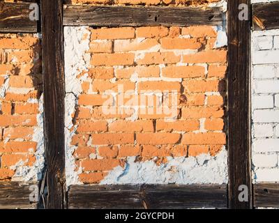 Detailansicht einer Fachwerkwand mit freiliegenden Ziegeln; Sandsteine und Zementflecken im Licht der Abendsonne. Stockfoto