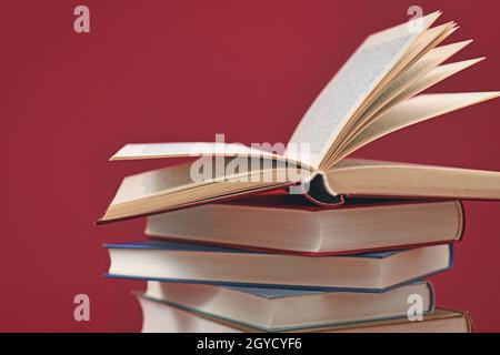 Stapel alter Hardcover-Bücher auf dunkelrotem Hintergrund Stockfoto