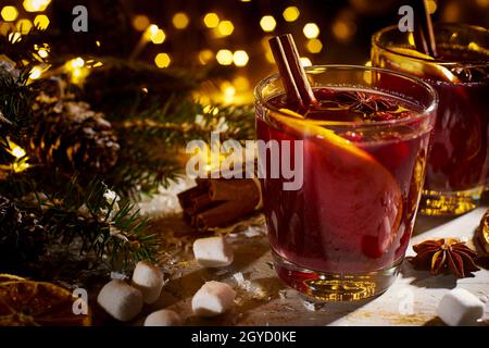 Glühwein mit Gewürzen und Früchten auf Holztisch Stockfoto
