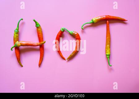 Wort scharf aus roten, scharfen, Chili-Paprika auf hellrosa Hintergrund Stockfoto