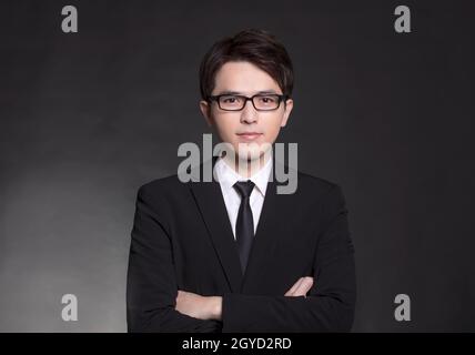 Junger, hübscher Geschäftsmann in schwarzem Anzug und Brille Stockfoto