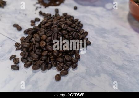 Kleiner Stapel gerösteter Kaffeebohnen auf weißer Oberfläche Stockfoto