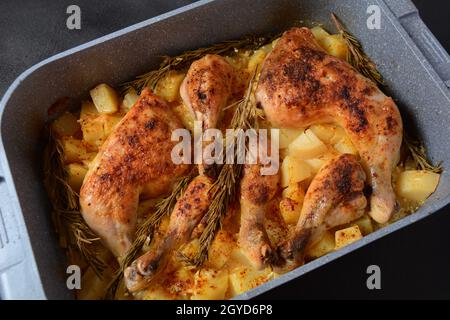 Gebackene Hähnchenschenkelvierteln und mit Knoblauch gewürzte Drumsticks und Kräutern mit Kartoffeln in einer Auflaufform Stockfoto