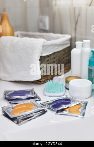 Einzeln verpackte goldene und blaue Augenaufnäher auf dem Tisch im Badezimmer. Hydrogelpflaster. Gesichtshautpflege. Stockfoto