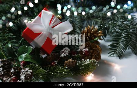 Rotes luxuriöses Weihnachtsgeschenk in Pinienästen eingebettet Stockfoto