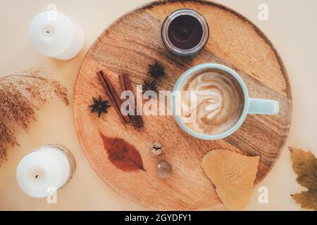 Eine Tasse Cappuccino mit Sternanise, Muskatnuss und Zimtschnecken auf einem Holztablett. Herbst flach liegend, heißer Drink, gemütliches Zuhause. Draufsicht. Stockfoto