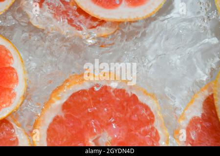 Nahaufnahme von frischen Scheiben roter Grapefruit auf weißem Hintergrund. Grapefruitscheiben in sprudelndem Wasser auf weißem Hintergrund, Nahaufnahme. Zitrussoda. Kopie en Stockfoto