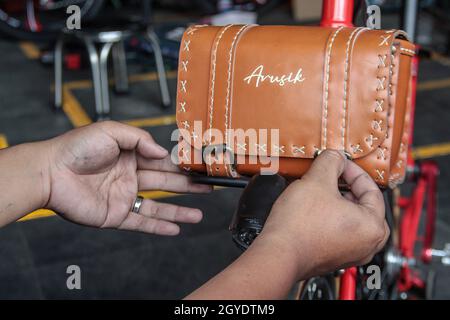 Bandung, Indonesien. Oktober 2021. Ein Mechaniker sah in der Werkstatt von Arusik Bikes in Bandung, wie er ein Batteriefach an einem Faltfahrrad installierte, das in ein Elektrofahrrad umgewandelt wird. Die Standard-Fahrrad-Innovation, die mit Strom modifiziert wird, basiert auf einem zusätzlichen Dynamo am Rad mit einem „Pedal Assist“- und „Gas-Gaspedal“-System, das bis zu 70 Kilometer hält. Die Custom-Akku-Power 'Arusik Bike' reicht von 250 bis 300 Watt bei einer Akkuladezeit von 4 Stunden von Null bis voll. Kredit: SOPA Images Limited/Alamy Live Nachrichten Stockfoto