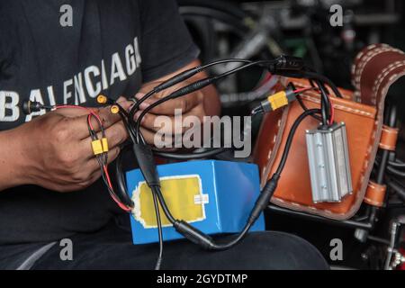 Bandung, Indonesien. Oktober 2021. Ein Mechaniker sah in der Werkstatt von Arusik Bikes in Bandung, wie er ein Batteriefach an einem Faltfahrrad installierte, das in ein Elektrofahrrad umgewandelt wird. Die Standard-Fahrrad-Innovation, die mit Strom modifiziert wird, basiert auf einem zusätzlichen Dynamo am Rad mit einem „Pedal Assist“- und „Gas-Gaspedal“-System, das bis zu 70 Kilometer hält. Die Custom-Akku-Power 'Arusik Bike' reicht von 250 bis 300 Watt bei einer Akkuladezeit von 4 Stunden von Null bis voll. Kredit: SOPA Images Limited/Alamy Live Nachrichten Stockfoto