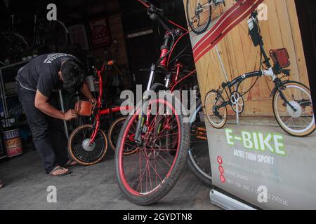 Bandung, Indonesien. Oktober 2021. Ein Mechaniker sah in der Werkstatt von Arusik Bikes in Bandung, wie er ein Batteriefach an einem Faltfahrrad installierte, das in ein Elektrofahrrad umgewandelt wird. Die Standard-Fahrrad-Innovation, die mit Strom modifiziert wird, basiert auf einem zusätzlichen Dynamo am Rad mit einem „Pedal Assist“- und „Gas-Gaspedal“-System, das bis zu 70 Kilometer hält. Die Custom-Akku-Power 'Arusik Bike' reicht von 250 bis 300 Watt bei einer Akkuladezeit von 4 Stunden von Null bis voll. Kredit: SOPA Images Limited/Alamy Live Nachrichten Stockfoto