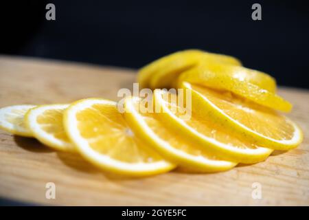 Frische orangefarbene Scheiben auf Holzoberfläche mit schwarzem Hintergrund Stockfoto