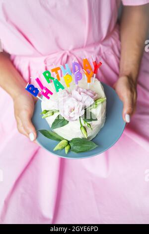 Happy Birthday Kuchen mit Buchstaben Happy Birthday in Form von Kerzen hält ein sehr buntes und sehr leckeres Mädchen in einem rosa Kleid in den Händen. Holida Stockfoto