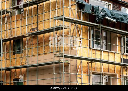 Dämmung der im Bau befindlichen Hausfassade mit Mineralwolle um die Fenster mit einem Gerüst, das ein Konzept der Wärmeeinsparung im Haus ist Stockfoto