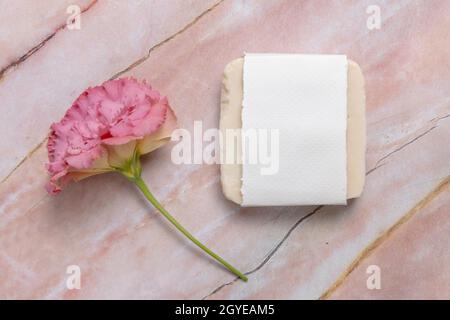 Seifenstück auf einem Marmortisch mit rosa Blüten, Draufsicht. Seifenmockup Stockfoto