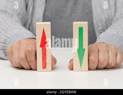 Weibliche Hand hält Holzblöcke mit auf- und Abwärtspfeilen. Das Konzept der Senkung und Erhöhung von Indizes, Wechselkurse. Dynamik Stockfoto