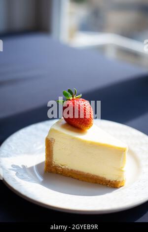 Scheibe köstlicher Erdbeer-Käsekuchen auf weißem Teller mit frischen Erdbeeren, Nahaufnahme Stockfoto