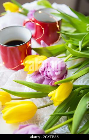 Schöner Morgen, zwei Tassen Kaffee und ein Bouquet von hellen Tulpen. Stockfoto