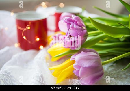 Schöner Morgen, zwei Tassen Kaffee und ein Bouquet von hellen Tulpen. Stockfoto