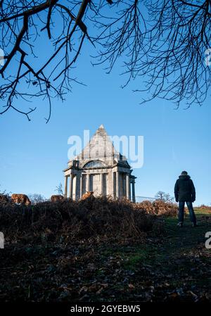 Ein Mann, der neben dem Darnley Mausoleum steht, einem restaurierten Mausoleum aus dem 18. Jahrhundert, das in einem friedlichen öffentlichen Wald liegt Stockfoto