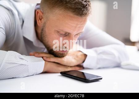 Mann Wartet Auf Telefonanruf Am Büroschalter Stockfoto