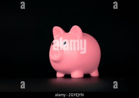 Pink Piggy Bank horizontal auf schwarzem Hintergrund mit Kopierraum, Business-, Sparungs- und Finanzkonzept-Schatten Stockfoto