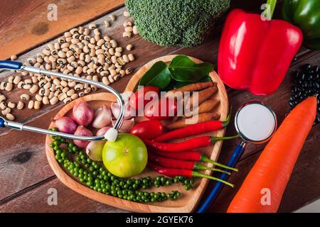 Weltessen-Tag, Draufsicht auf verschiedene frische Bio-Obst und Gemüse in Herzplatte und Arzt Stethoskop mit Kopierer Platz, Studio auf Holzregale aufgenommen Stockfoto