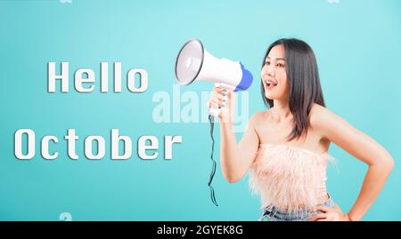 Hallo Oktober, lächelndes Gesicht Porträt Asian schöne junge Frau sie mit Megaphon Hallo Studio auf blauem Hintergrund aufgenommen sagen Stockfoto