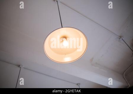 Blick aus dem unteren Winkel auf eine Lampe, die von der weißen Decke hängt Stockfoto