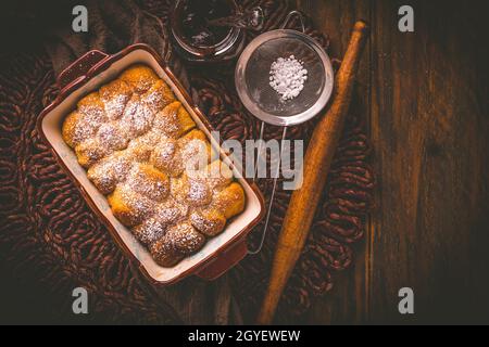 Buchteln gefüllt mit Pflaumenkonfitüre oder Gelee, süße Brötchen mit Backzutaten Stockfoto