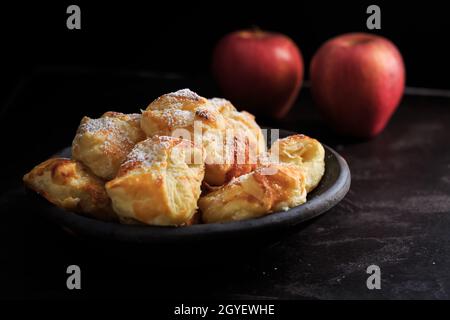 Hausgemachte kleine Apfel-Turnover in Schale auf schwarzem Hintergrund Stockfoto