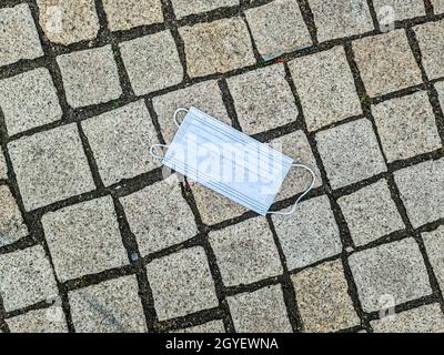 Nahaufnahme einer OP-Maske, die in der Maske abgelegt und aufgegeben wurde Die Straße während der Coronavirus-Krise Stockfoto